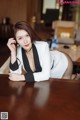 A woman in a white suit sitting at a table.