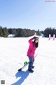 A woman in a pink jacket holding a snowboard in the snow.