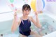 A woman in a bathing suit sitting in a bathtub with balloons.