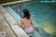 A woman in a pink bikini sitting in a pool.