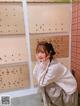 A woman sitting in front of a wall with a sign that says "Biscuit Q-Pot Japan"