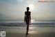 A woman in a bikini walking on the beach.