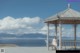 A woman sitting on a bench in front of a gazebo.