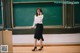 A woman standing in front of a blackboard talking on a cell phone.